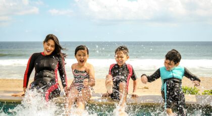 A family having fun splashing water near the seashore on a sunny day in Bali, Indonesia.