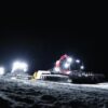 Illuminated snow groomers working at night in Zermatt, Switzerland during winter.