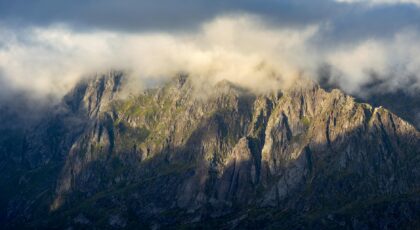 Majestic Lofoten mountain landscape draped in dramatic clouds at sunset.