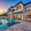 Elegant modern villa featuring an infinity pool and scenic hill views during sunset.