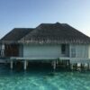 A serene overwater bungalow under a sunny sky, offering a perfect tropical getaway.