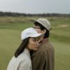 A young couple in casual attire embracing on a serene outdoor golf course.