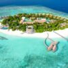 Aerial view of a serene tropical island resort surrounded by crystal-clear waters.