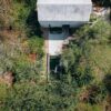 Aerial shot of a modern house with a pool amidst lush greenery, conveying tranquility.