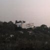 Charming villa nestled on a hill with a serene sea view, surrounded by lush greenery.