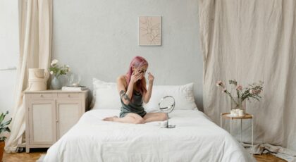 Young woman enjoying a skincare routine in a minimalist bedroom, surrounded by nature-inspired decor.