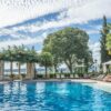 Enjoy a serene day by the luxurious tropical resort poolside, surrounded by palm trees and clear blue skies.