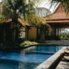 Relax by a luxurious tropical pool surrounded by lush palm trees under a sunny sky, perfect for summer getaways.
