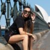 Stylish woman posing by the iconic Sydney Opera House on a sunny day, showcasing modern fashion.