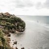 A breathtaking view of lush cliffs and a serene beach with waves gently washing ashore.