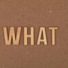 Wooden letters spelling 'What' on a brown cardboard background, close-up view.