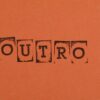 Close-up of the word OUTRO stamped on orange paper, highlighting typography and design.