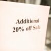 Close-up of a sale sign offering an additional 20% discount in a store window.