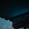 A glowing open sign in Russian under a canopy during nighttime.